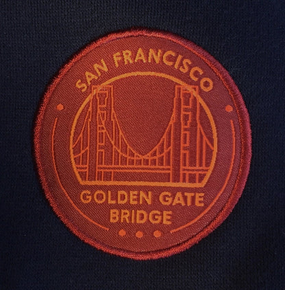 Navy blue hoodie with orange hood-lining accent and embroidered orange and red Golden Gate Bridge logo on left chest.