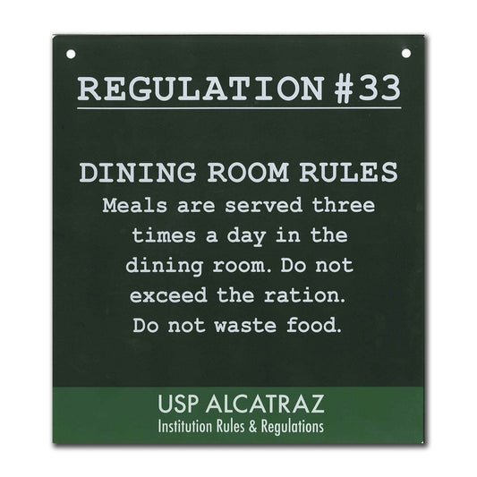 Black and green decorative metal sign with Alcatraz Regulation 33 ("Meals are served three times a day...") printed in white.