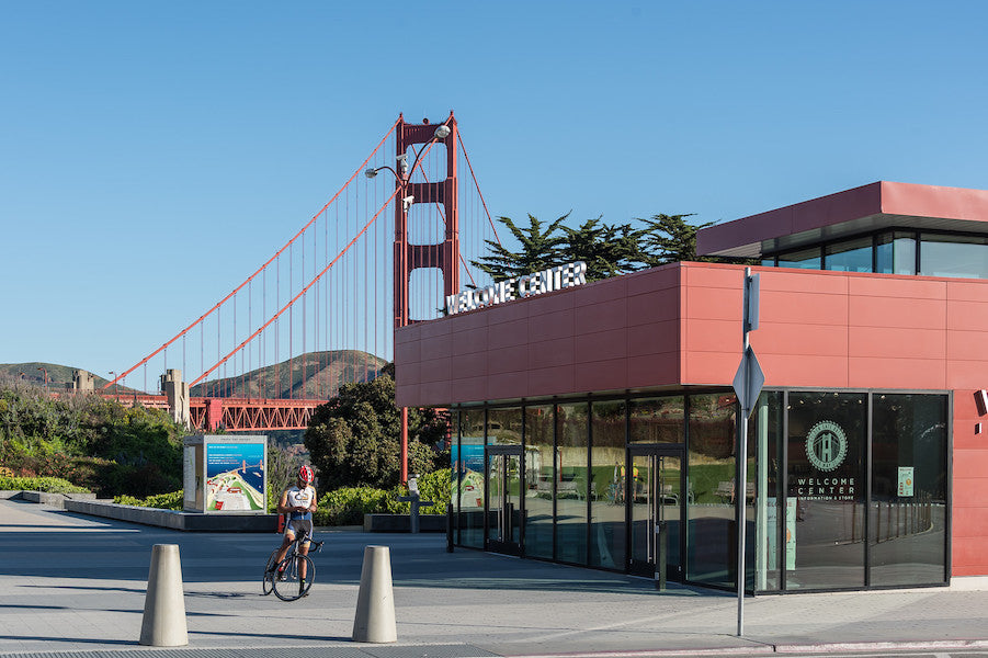The Golden Gate Bridge Welcome Center and Plaza, with the Golden Gate Bridge in the background. A bicyclist rests in the foreground.
