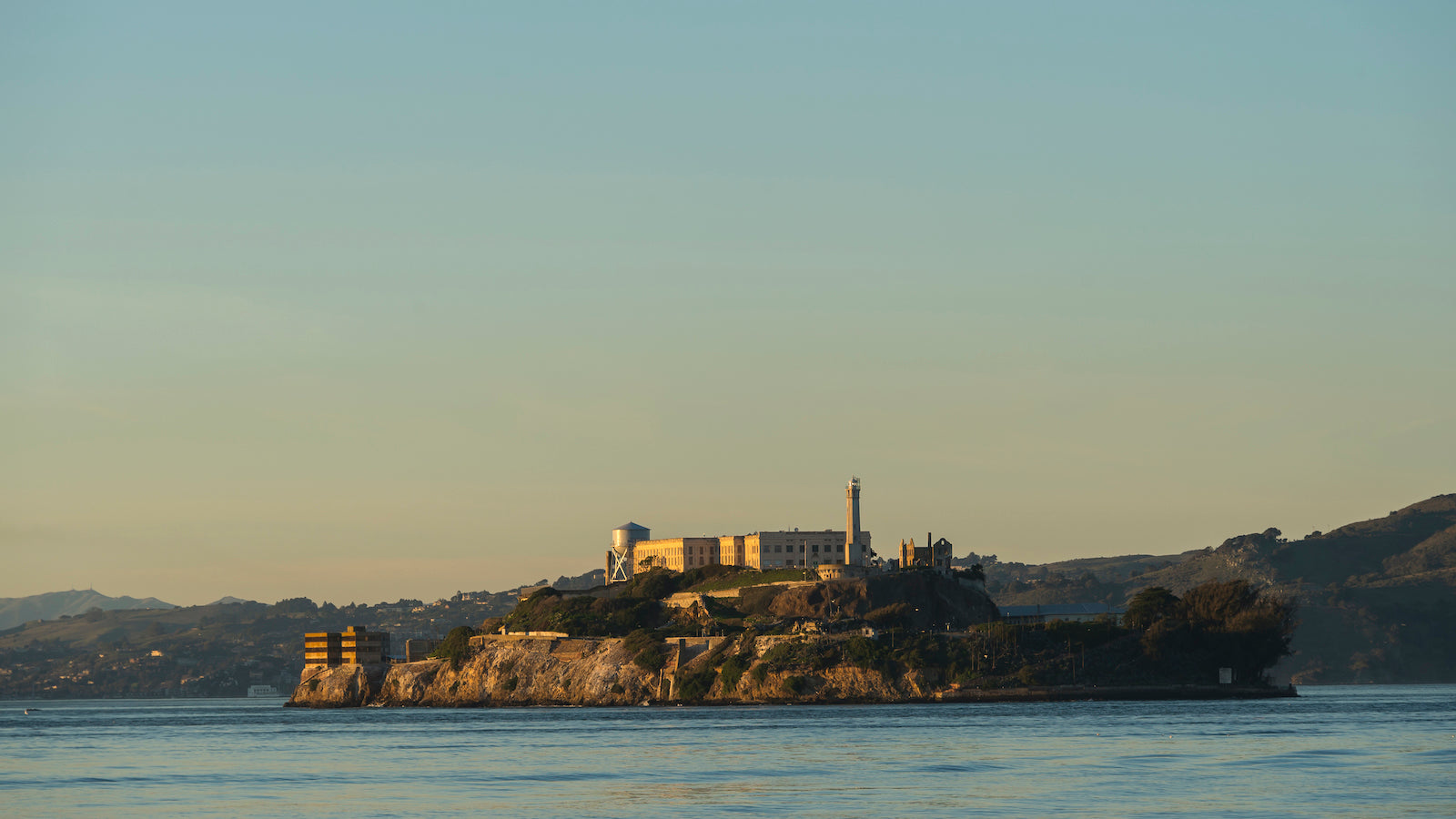 Alcatraz island in the late afternoon sun, surrounded by the blue waters of San Francisco Bay