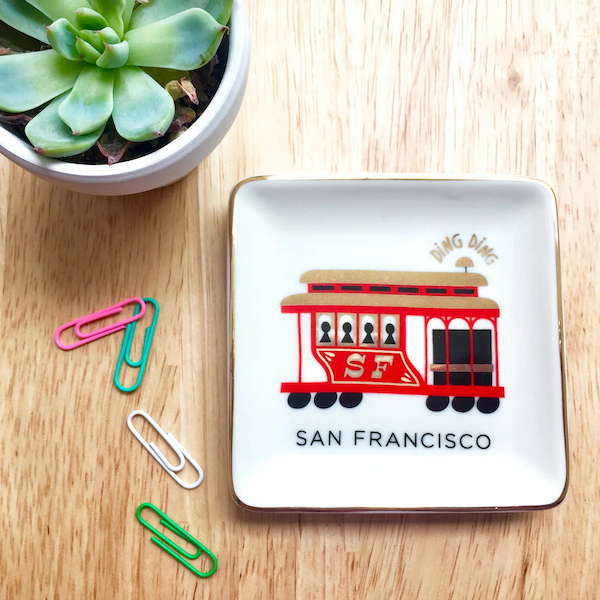 Small ceramic dish on wooden table top with San Francisco cable car design, with small succulent and colorful paperclips