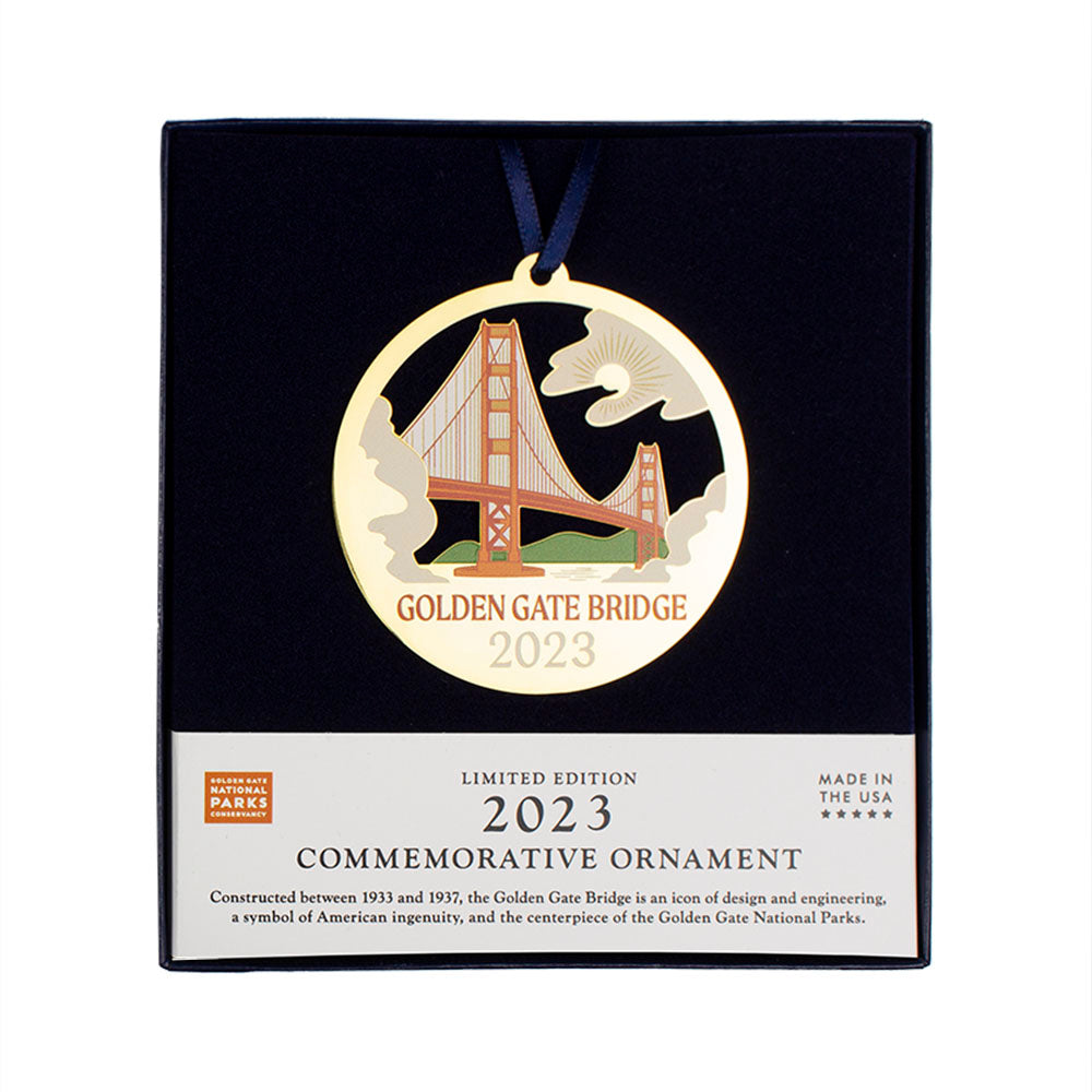 Limited edition 2023 commemorative ornament by the Golden Gate National Parks Conservancy, a circular gold ornament with multicolor Golden Gate Bridge giclee print design