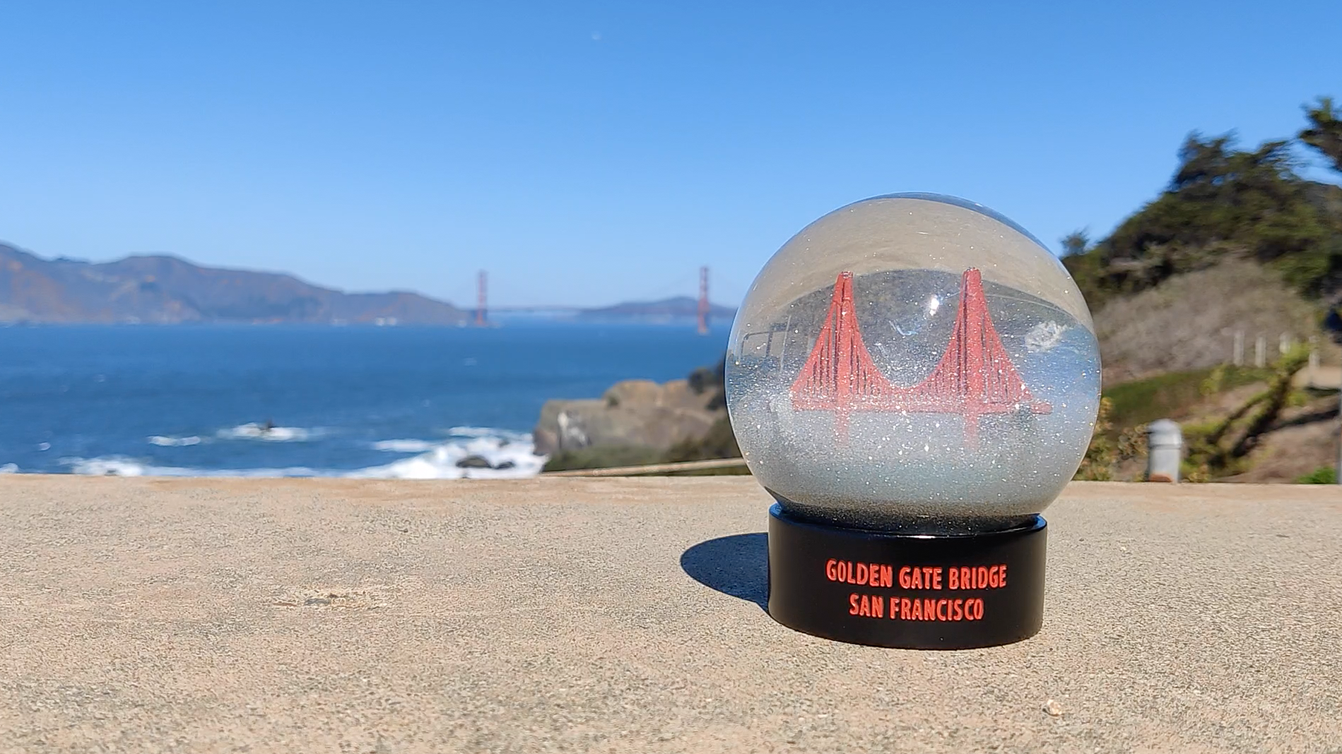 A Golden Gate Bridge fog globes sits on an old military gun battery with a wide view of the Golden Gate Bridge and Strait in the background.