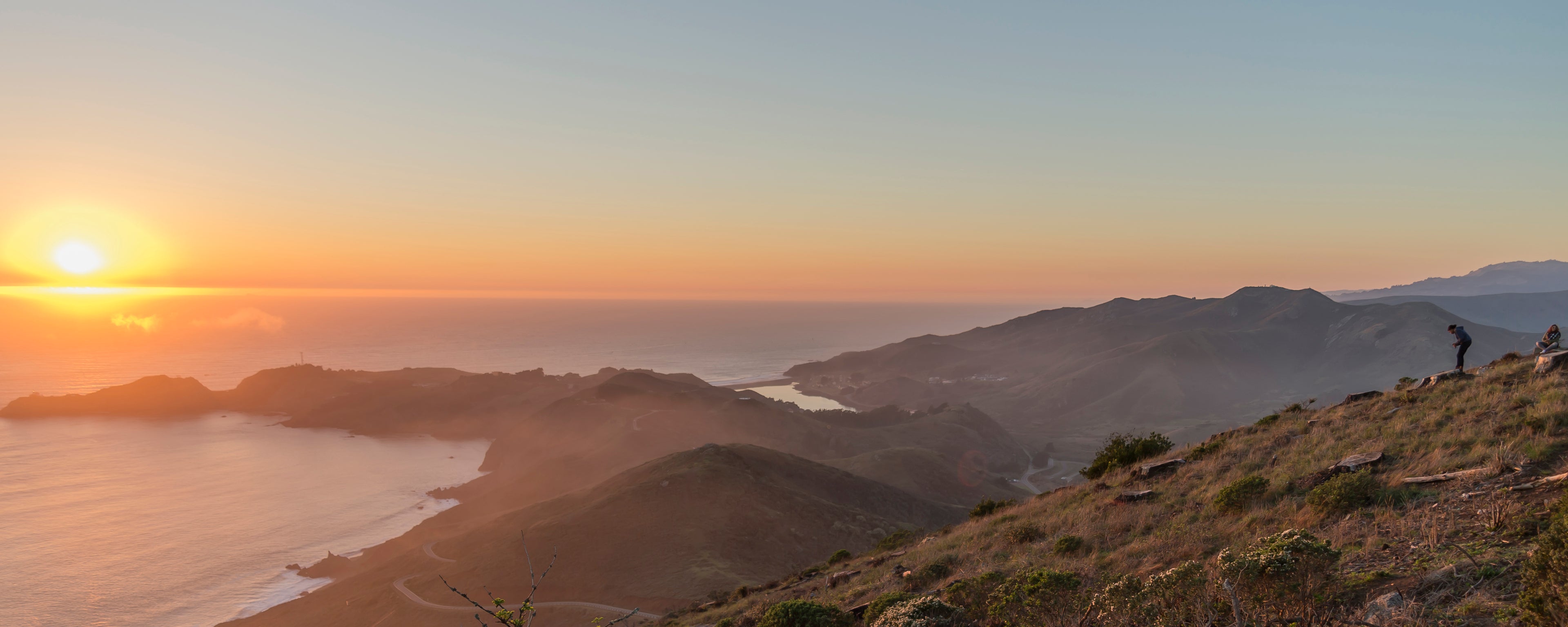 The sun sets over Rodeo Lagoon in the Marin Headlands, just north of San Francisco. The scene is illuminated by a warm glow.