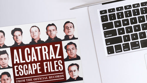 Alcatraz Escape Files book on a table with open laptop.