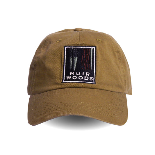 Tan khaki baseball cap with colorful embroidered logo on front panels, featuring illustration of redwood trees and text reading “Muir Woods”. Art by Michael Schwab.