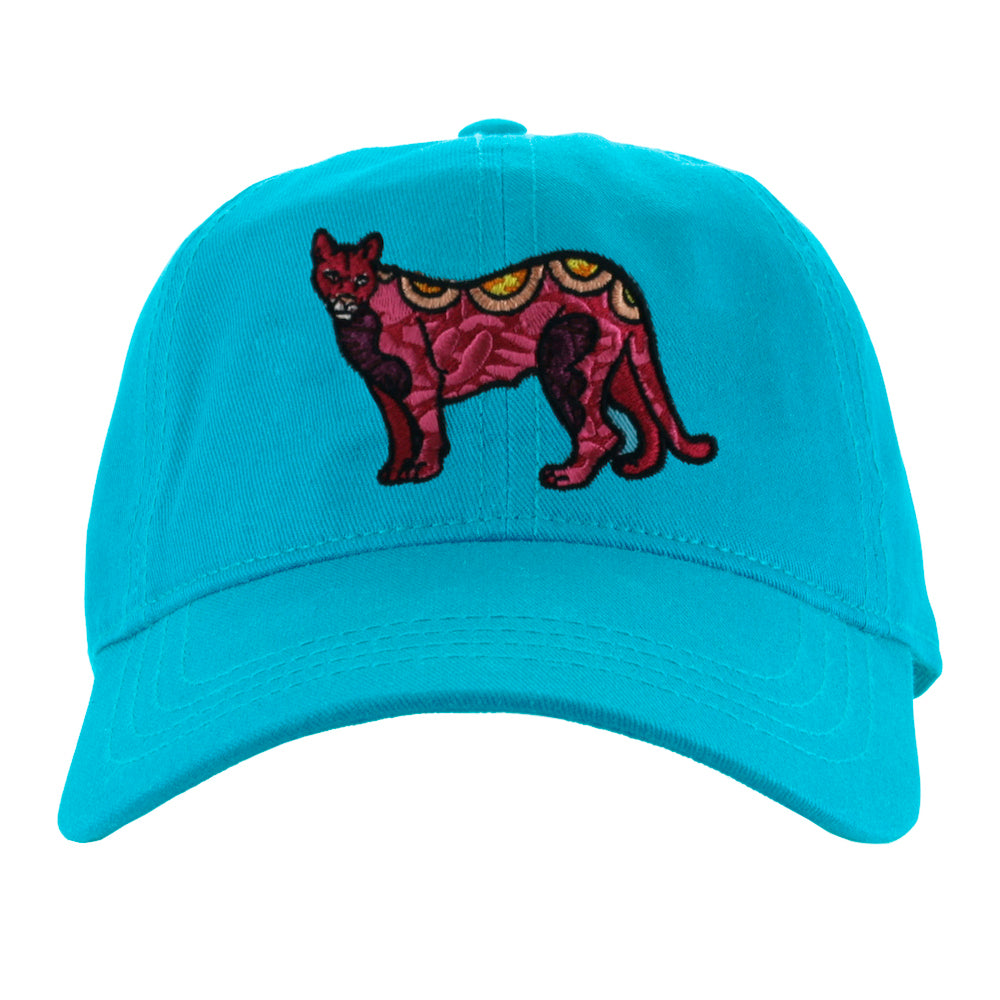 Bright blue cap with playfully embroidered mountain lion art by Favianna Rodriguez, from 2022 installation Ancestral Futurism